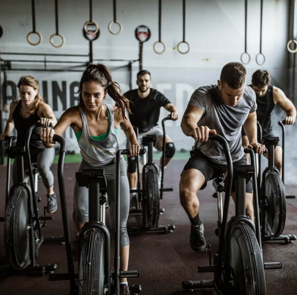Group of focused individuals in athletic wear participating in an intense cycling workout at a modern gym