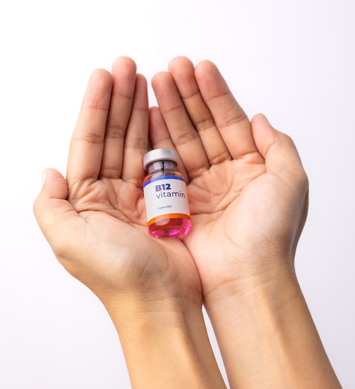 Image of hands holding up a small vial of B12 vitamin serum