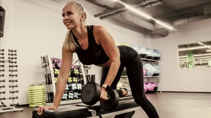 Woman doing a dumbbell row in a gym